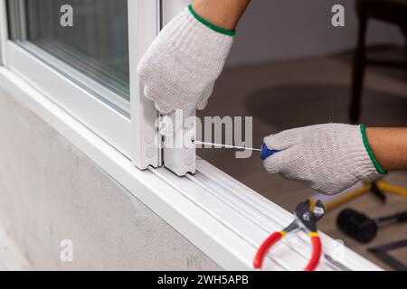 Construction worker repairing the sliding window. Open cap of adjust rail wheel. Stock Photo