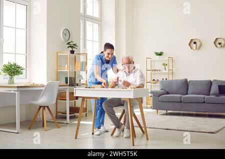 Demented senior man together with nurse playing games and doing puzzles in retirement home Stock Photo