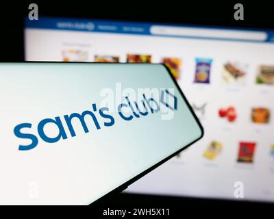 Cellphone with logo of American membership-only retail stores company Sam's Club in front of website. Focus on center-left of phone display. Stock Photo