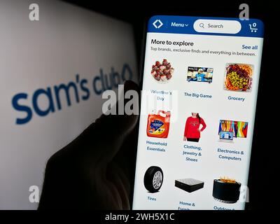 Person holding smartphone with webpage of US membership-only retail stores company Sam's Club in front of logo. Focus on cente rof phone display. Stock Photo