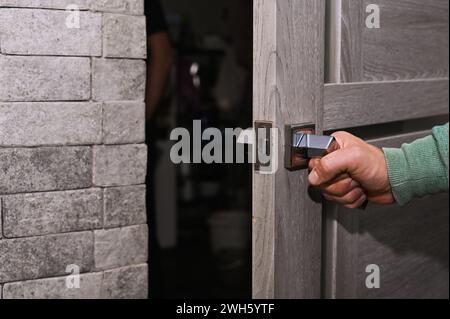 The man's hand opens the door in the room Stock Photo