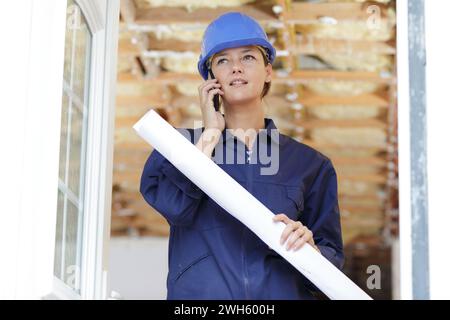 woman builder with blueprints using smart phone Stock Photo