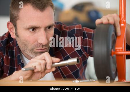 man repairing trolley with a wheel Stock Photo