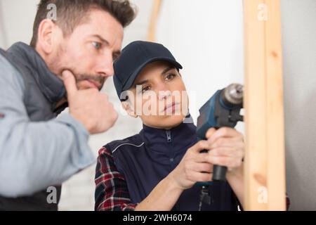 female apprentice carpenter using drill under supervision Stock Photo