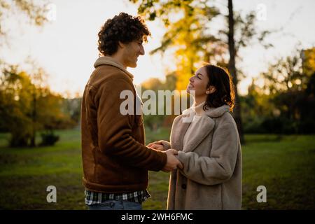 Portrait of happy loving couple in park in sunset. Couple in silhouette looking at each other. Stock Photo