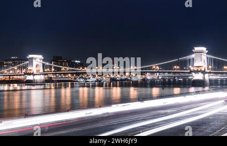 Cars drive along the water, with city lights streaking through Stock Photo