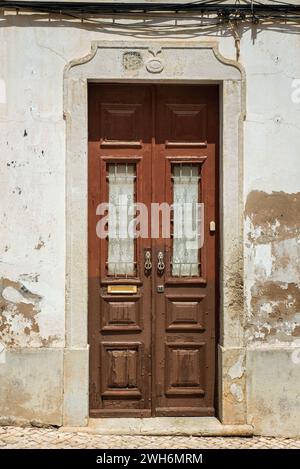An old wooden brown double door with glass panels in Lagos, Portugal Stock Photo