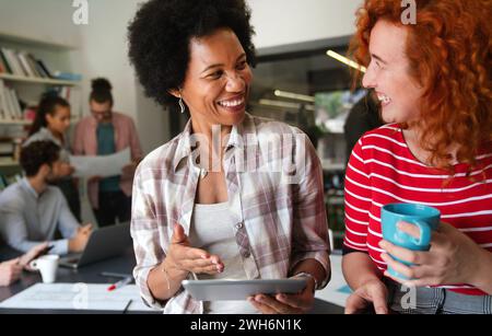 Two businesswoman working together using digital tablet pc and talking about a business project. Stock Photo