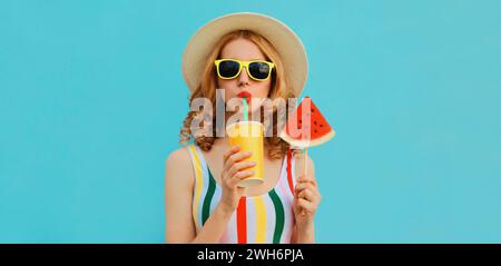 Summer fashionable colorful portrait of stylish young woman drinking juice with lollipop or ice cream shaped slice of watermelon wearing a straw hat o Stock Photo