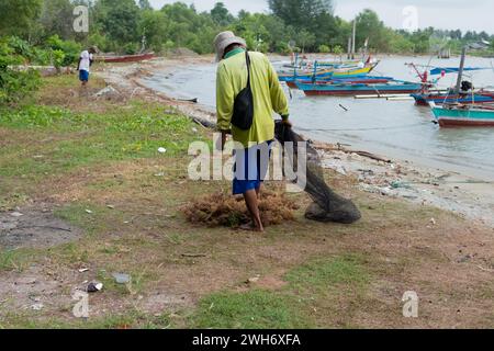 Asian man drying the sea. The harvested algae are dried in the sun or drained before being sold. Stock Photo