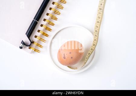 Chicken egg and measuring tape and pen on white background. Dieting concept Stock Photo