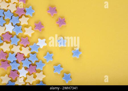 Colorful sugar sprinkles on yellow background Stock Photo