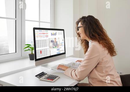 Woman working sitting at the desk with computer and talking to colleague via videochat. Stock Photo