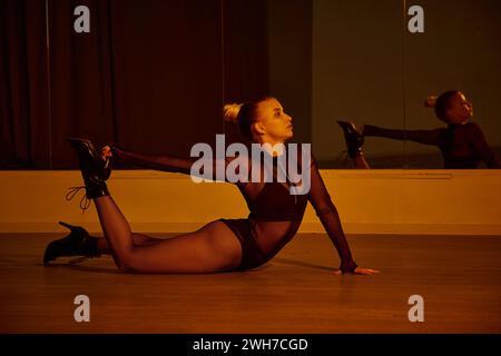 woman strikes a pose while showcasing her balance and fluidity in a black leotard and high heels Stock Photo