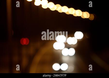 car headlights driving along illuminated motorway at night defocussed conceptual blurred image Stock Photo