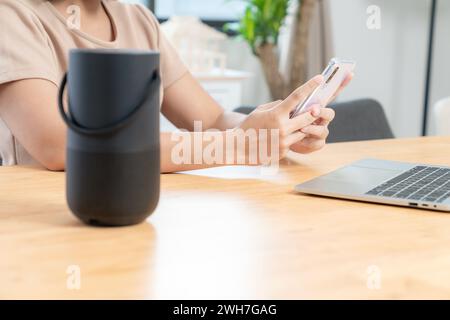 Young woman connecting a portable speaker at home Stock Photo