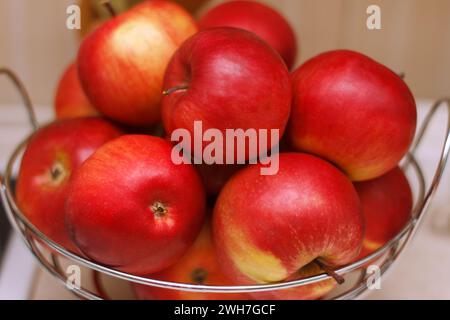 beautiful big ripe apples lie in a plate on a kitchen table Stock Photo
