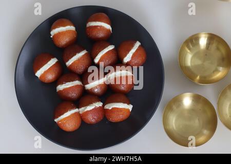 Malai Gulab Jamun. Gulab Jamun sandwich with milk cream filling. Fusion of Indian sweet dessert, golden brown, soft, and soaked in sugar syrup. Perfec Stock Photo