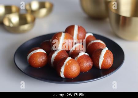 Malai Gulab Jamun. Gulab Jamun sandwich with milk cream filling. Fusion of Indian sweet dessert, golden brown, soft, and soaked in sugar syrup. Perfec Stock Photo