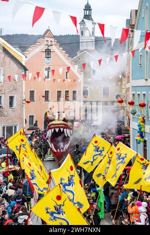 Dietfurt, Germany. 08th Feb, 2024. A Chinese dragon can be seen in the parade at the traditional Chinese carnival. As every year on 'Nonsensical Thursday', jesters dressed as Asians parade through the town. The Chinese carnival goes back to a legend according to which the people of Dietfurt simply left a tax collector standing outside the town wall in the Middle Ages. The treasurer is said to have subsequently complained to the bishop, his employer, that the people of Dietfurt were hiding behind their wall 'like the Chinese'. Credit: Armin Weigel/dpa/Alamy Live News Stock Photo