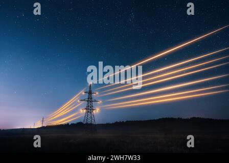 Electricity transmission towers with orange glowing wires the starry night sky. Energy infrastructure concept. Stock Photo