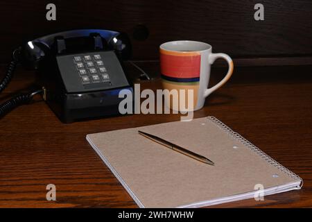 Gold pen on notebook on wood desk in home office,retro phone Stock Photo