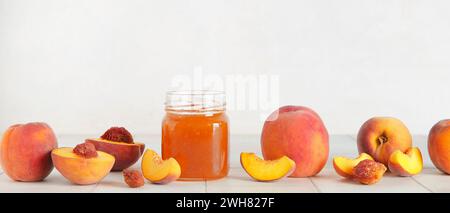 Fresh peaches and sweet jam in jar on table against white background Stock Photo