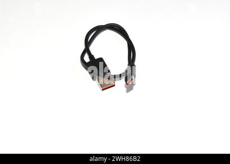 A twisted black USB cable lies on a white background. Stock Photo