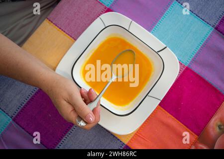 Hand with spoon to eat a carrot soup Stock Photo