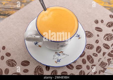 Coffee in small cup with dish and spoon on dish towel and old wooden color table Stock Photo