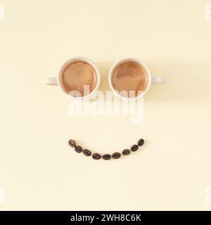Layout of smiley emoticon made with coffee cups and coffee beans on pastel background. Minimal coffee concept. Creative positive thinking, good mood. Stock Photo