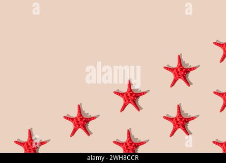 Summer pattern composition made with red starfish on sandy color background. Minimal summer concept. Creative sea star flat lay pattern idea. Stock Photo