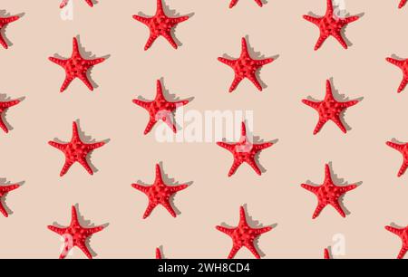 Summer pattern composition made with red starfish on sandy color background. Minimal summer concept. Creative sea star flat lay pattern idea. Stock Photo