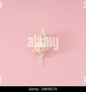 Trendy summer layout of sea shell with ice cream stick on light peachy pink background. Minimal summer concept. Creative beach food idea. Stock Photo