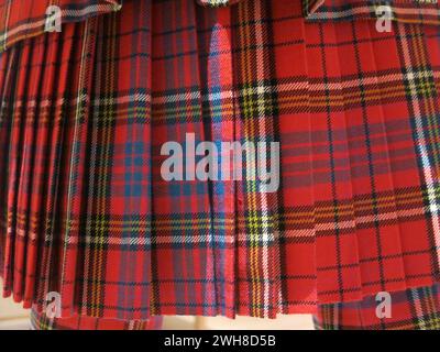The pleated fabric recognised the world over as Scottish tartan, in this example a red checked pattern with the heavy folds to make a swinging kilt. Stock Photo