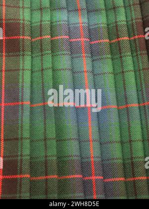 Traditional Scottish tartan with a green background and horizontal & vertical red stripes making the blocks of pattern in this famous, pleated fabric. Stock Photo