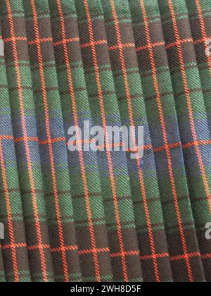 Traditional Scottish tartan with a green background and horizontal & vertical red stripes making the blocks of pattern in this famous, pleated fabric. Stock Photo
