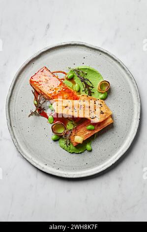 Grilled salmon fillet, miso potato gratin, edamame & leek cream, sesame tuile Stock Photo