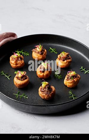 Mini Yorkshire puddings, merlot braised pulled beef, sticky shallot jam, horseradish emulsion, soft herbs Stock Photo