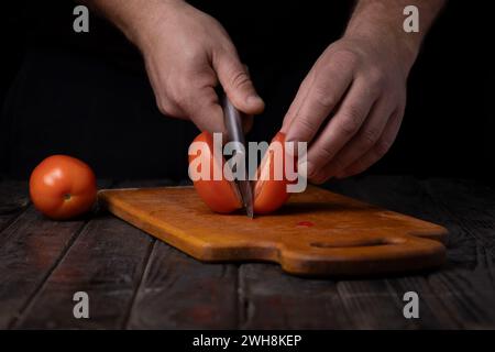 Cutting vegetables. Male hands cutting tomatoes on a cutting board Stock Photo