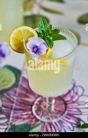Lemon Mint Lemonade Mocktail on Floral Background with Lemon, Mint and Purple Flower Decor Stock Photo