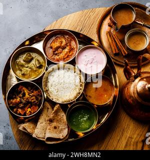 Indian food Thali  Indian-style meal with chicken meat and Masala tea Chai on wooden table Stock Photo