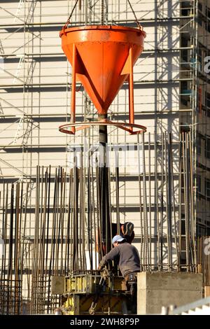 Construction site, construction workers, pouring concrete mix, reinforcement form, cement mix pouring, construction site, occupation, charging hopper Stock Photo