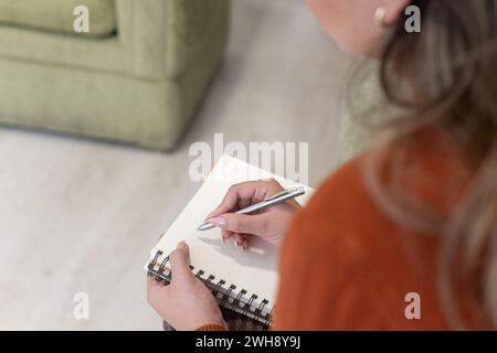 close-up of a woman's hand from her back taking notes in a notebook with a pen Stock Photo