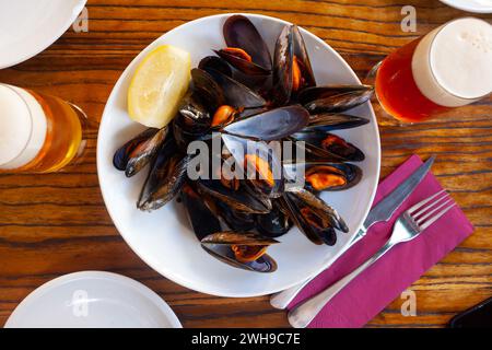 Steamed mussels with lemon wedge on white plate Stock Photo