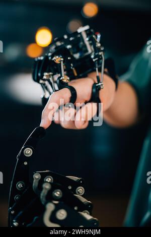At a technical college a teen boy learns technology by testing a robot hand and arm touching fingers Stock Photo