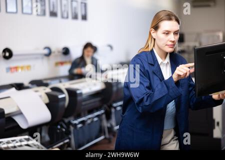 Technician operator calibrating plotter machine, typing on computer keyboard Stock Photo