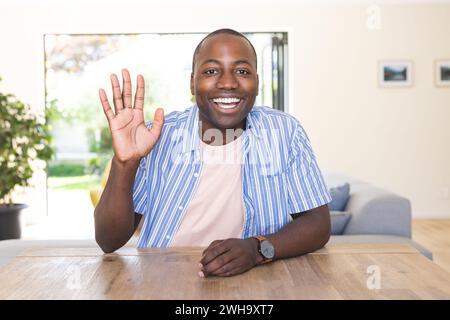 Young African American man waves cheerfully at home on a video call Stock Photo