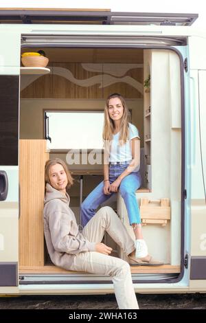 Two young person enjoy a comfortable ride in the entrance of a luxurious campervan. Stock Photo