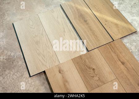 Top View Luxury Vinyl Wood Samples Lying On Concrete Floor In House. Choosing, Selecting Waterproof Flooring. Home Reconstruction. Vinyl Tiles Stock Photo